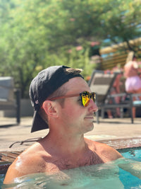 Guy wearing redwood sustainable wooden sunglasses at the pool to protect eyes and look stylish